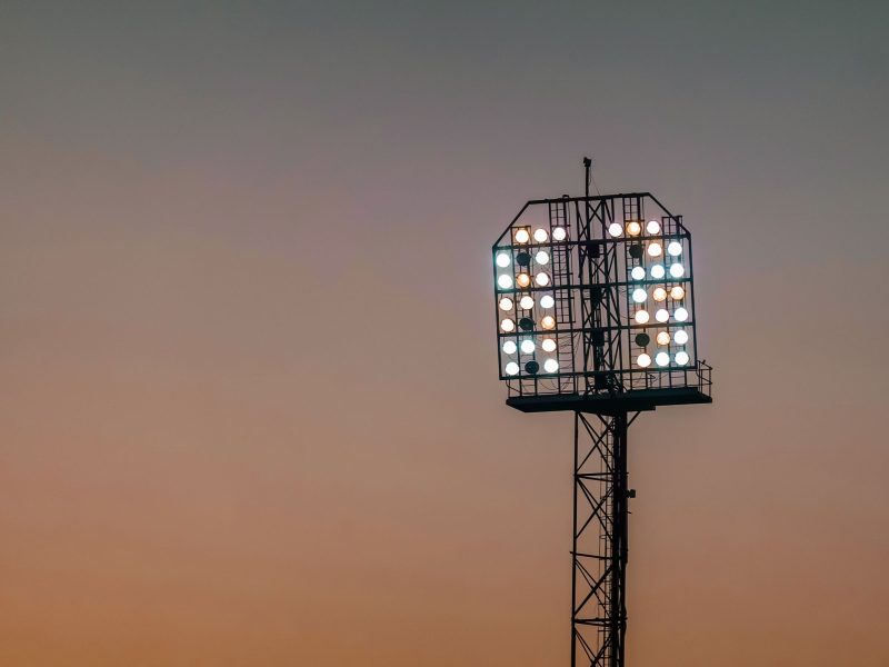 Flutlichtmast eines Sportplatzes vor orangefarbenem Abendhimmel